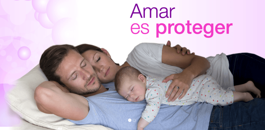 Una familia descansando junta. Un hombre y una mujer están acostados, abrazando a su bebé, que también duerme. En el fondo, sobre un degradado en tonos rosas, aparece el texto "Amar es proteger"